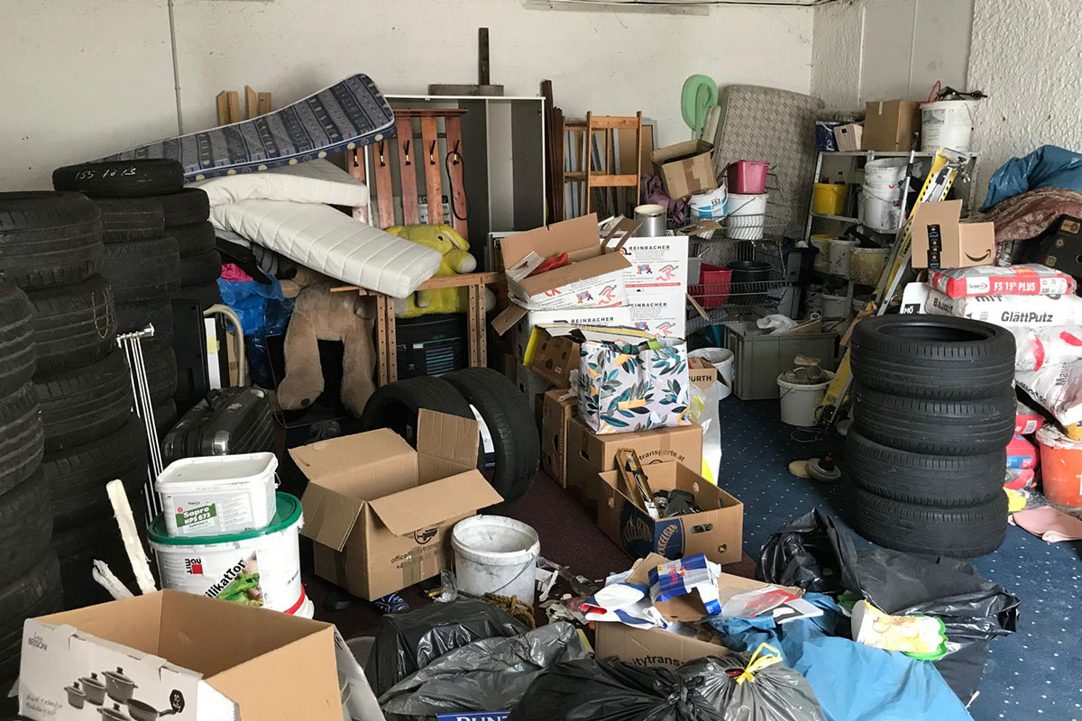 Garagenräumung Graz vorher – stark überfüllte Garage mit Möbeln, Kartons und Reifen vor der Entrümpelung
