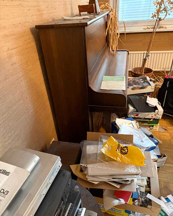 Vollgestelltes Zimmer mit Klavier vor Entrümpelung – Möbelentsorgung Graz