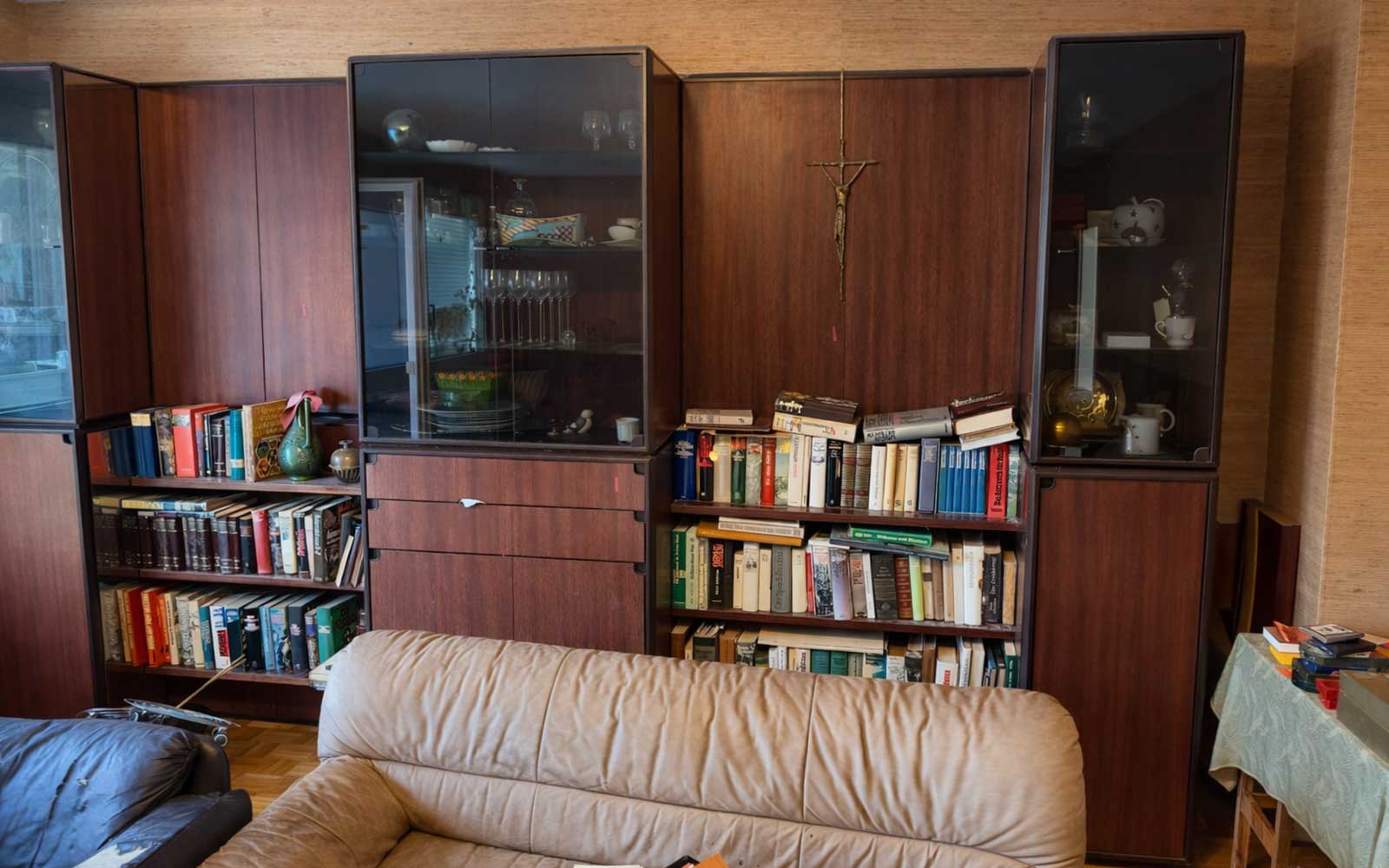Wohnzimmer einer Wohnung in Graz vor der Wohnungsräumung mit Möbelwand, Büchern und Sofa